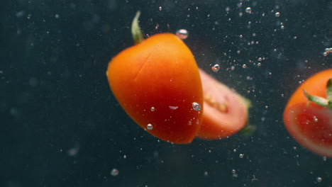 Stücke-Geschnittener-Tomaten-Unter-Wasser-Mit-Luftblasen-Und-In-Zeitlupe.-Frische-Und-Saftige-Gesunde-Vegetarische-Produktsalatzutaten